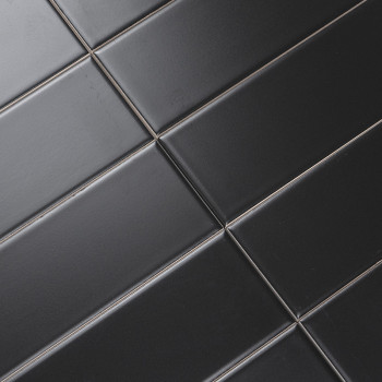 Les carreaux rectangulaires noirs sont alignés en diagonale selon un motif de grille, créant une surface élégante et moderne ave