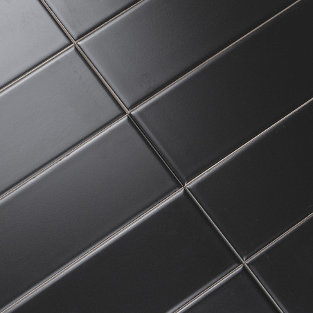 Les carreaux rectangulaires noirs sont alignés en diagonale selon un motif de grille, créant une surface élégante et moderne ave