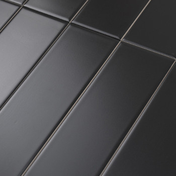 Les carreaux rectangulaires mats foncés sont alignés selon un motif décalé, créant une surface moderne et homogène. Le contexte 