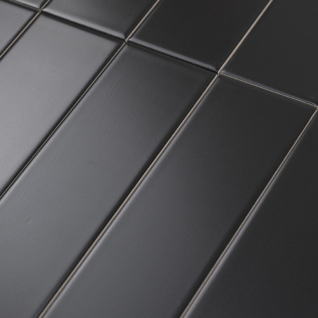 Les carreaux rectangulaires mats foncés sont alignés selon un motif décalé, créant une surface moderne et homogène. Le contexte 