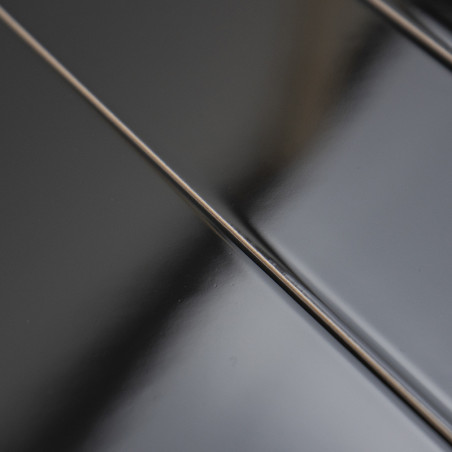 Smooth, glossy black tiles lay side by side, reflecting light subtly, creating a sleek and modern surface.