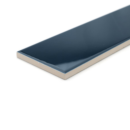 A rectangular, glossy dark blue ceramic tile lies isolated on a white surface, showcasing its smooth, reflective finish and thic