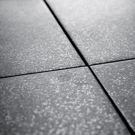 Les carreaux de céramique grises se croisent, formant un motif en forme de grille. Chaque carreau est moucheté d’une texture lég