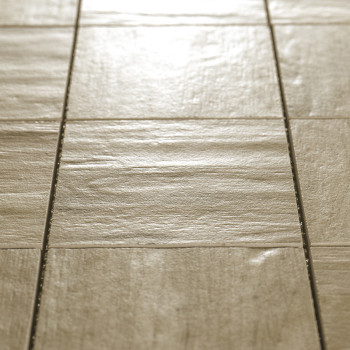 Vierkante beige tegels uitgelijnd in een rasterpatroon, dat licht reflecteert, gelegen op een vlak binnenvloeroppervlak.