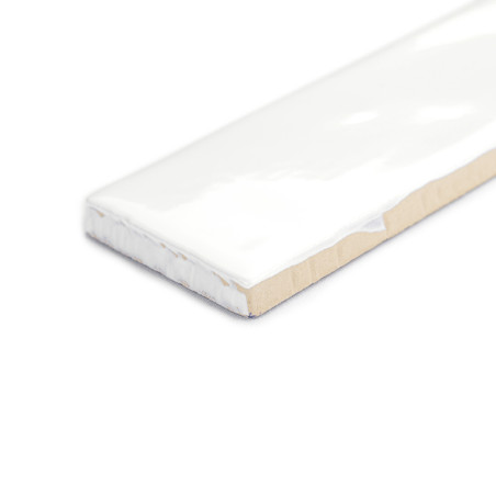 Un carreau rectangulaire au fini blanc brillant repose debout sur un fond blanc, mettant en valeur sa surface lisse et ses bords