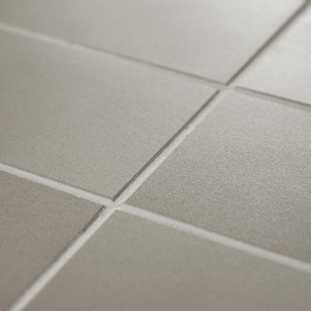 Les carreaux carrés mats forment un motif de grille, semblant uniforme et ordonné, avec une texture subtile sous un éclairage do