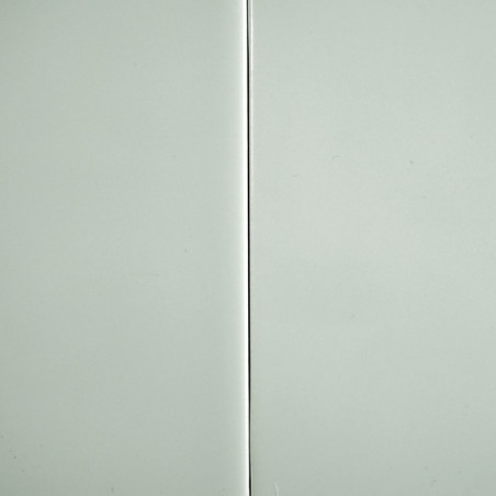 Un azulejo gris claro brillante con una costura vertical divide la superficie, sobre un fondo liso.