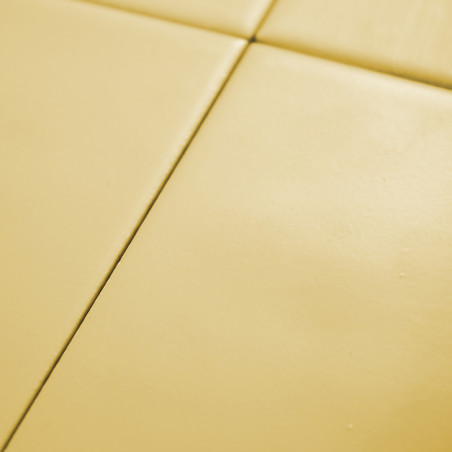 Cuatro azulejos amarillos lisos forman una cuadrícula, creando un patrón geométrico minimalista sobre una superficie plana.