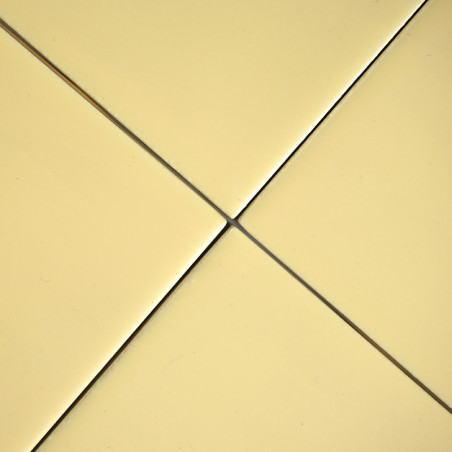 Cuatro azulejos lisos, cuadrados y de color amarillo pálido se unen en el centro, formando un patrón de cruz simétrico. cada los