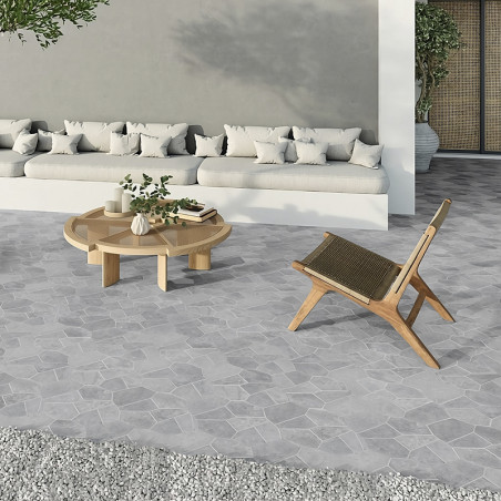 Gray stone tiles form the floor, displaying a geometric pattern beneath a wooden chair and round table outside.