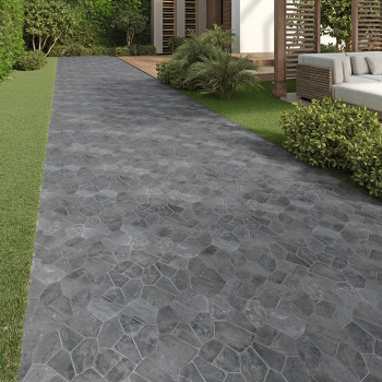 Gray stone tiles form a pathway, leading through a garden with green bushes and a modern patio.