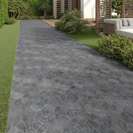 Gray stone tiles form a pathway, leading through a garden with green bushes and a modern patio.