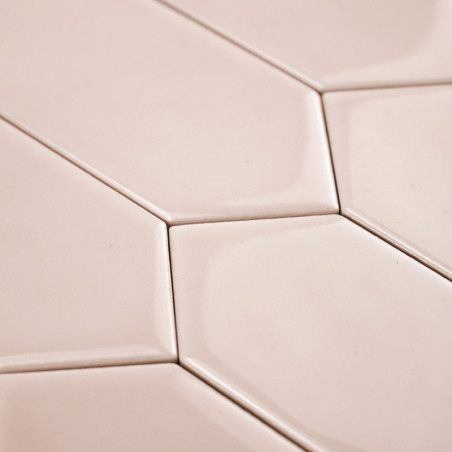 Ladrilhos hexagonais bege se interligam perfeitamente, criando um padrão geométrico. A superfície lisa e brilhante reflete a luz