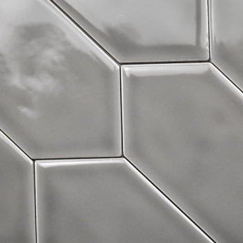 Ladrilhos cerâmicos cinza brilhantes formam um padrão geométrico com bordas elevadas e angulares, criando uma textura elegante e