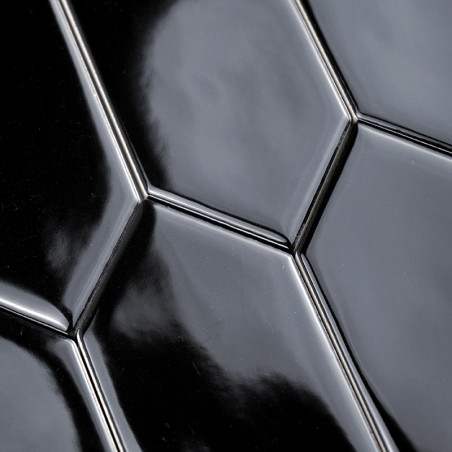Ladrilhos cerâmicos pretos lisos e brilhantes, dispostos em um padrão hexagonal repetido, refletem a luz em um ambiente interno,