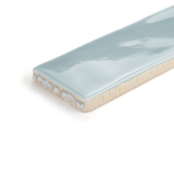 Un azulejo cerámico rectangular con una superficie azul claro brillante descansa sobre un fondo blanco liso, mostrando su acabad