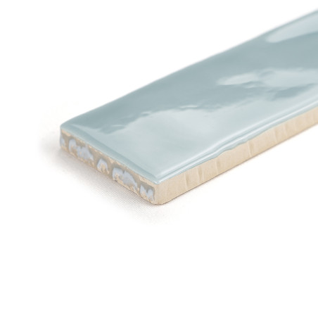 Un azulejo cerámico rectangular con una superficie azul claro brillante descansa sobre un fondo blanco liso, mostrando su acabad