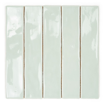 A long, narrow, glossy pale green ceramic tile rests against a plain white background, showcasing its smooth, reflective surface