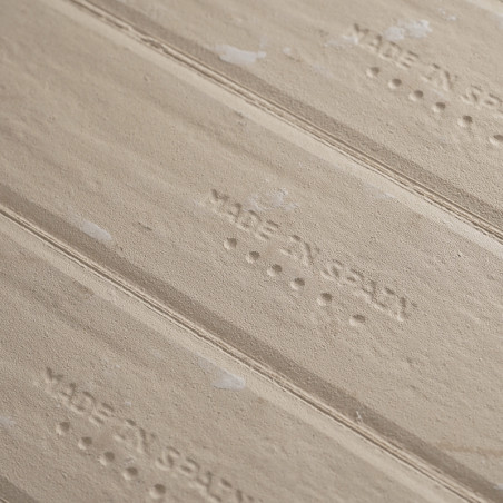 Les carreaux de céramique beige en relief, affichant « MADE IN SPAIN », sont alignés horizontalement et ornés de subtiles marque