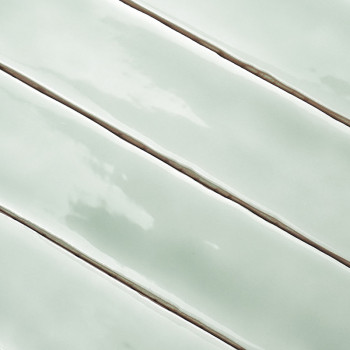 Glossy, light green rectangular tiles are aligned with narrow, darker grout lines, creating a smooth, uniform appearance in a cl