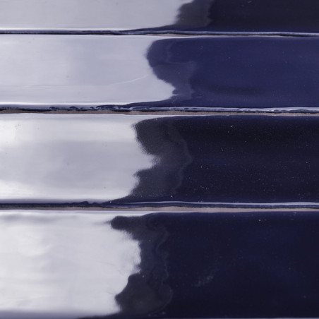 Les carreaux de céramique brillants d'un bleu profond réfléchissent la lumière, créant un motif brillant semblable à une vague. 