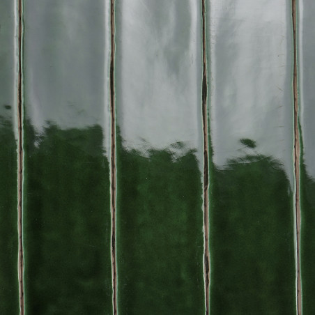 Los azulejos de cerámica de color verde brillante se colocan verticalmente y reflejan la luz. La alternancia de tonos claros y o