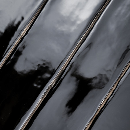 Les carreaux noirs brillants reflètent la lumière, créant un effet miroir ondulé. La surface apparaît humide, mettant en valeur 