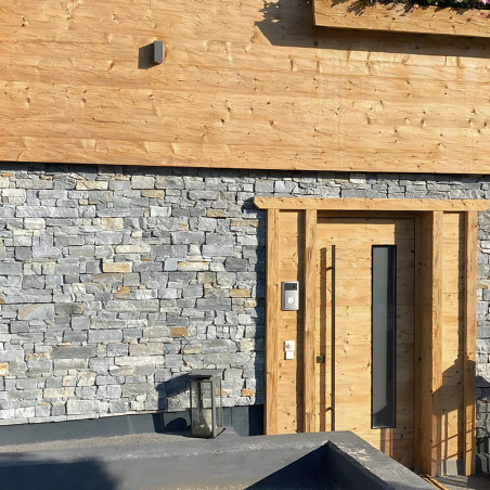 Stone tiles create a textured wall beside a wooden door in a modern residential entrance.