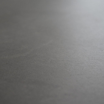 Un azulejo gris liso y liso yace plano, mostrando una textura mate sutil, sin patrones visibles ni objetos circundantes a la vis