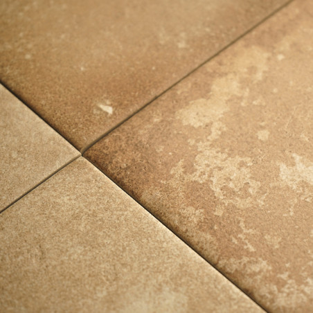 Quatre carreaux beiges forment une grille, présentant une surface texturée et de subtiles variations de couleurs, disposées selo
