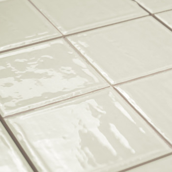 Azulejos cuadrados brillantes de color blanquecino dispuestos en forma de cuadrícula. reflejan la luz, creando una superficie el