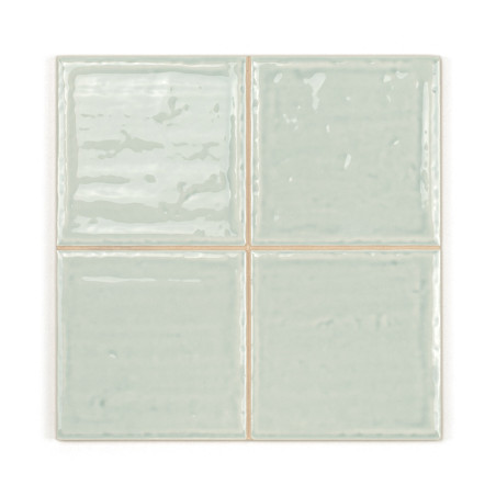 Four glossy, light green ceramic tiles, slightly reflective, arranged in a 2x2 grid. The tiles exhibit subtle, irregular texture