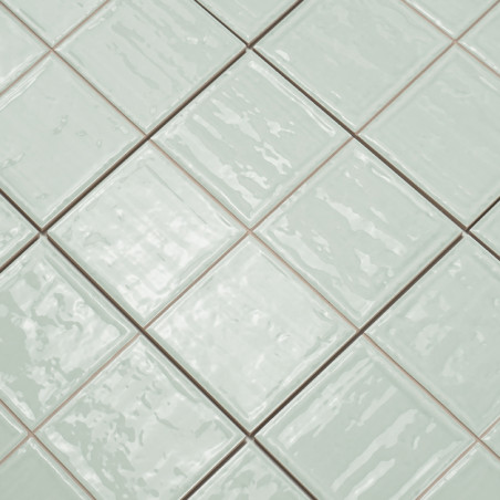 Square ceramic tiles with a glossy, light green finish are arranged neatly in a grid pattern, creating a uniform surface.