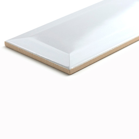 A rectangular ceramic tile rests on a white surface, displaying a glossy finish with beveled edges, reflecting soft lighting.