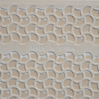 Un azulejo beige muestra un patrón semicircular elevado en un diseño geométrico repetido. En el texto central se lee `MADE IN SP