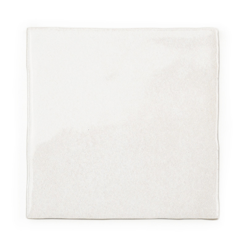 A square white tile sits stationary, presenting a smooth, slightly textured surface. The plain background emphasizes its minimal