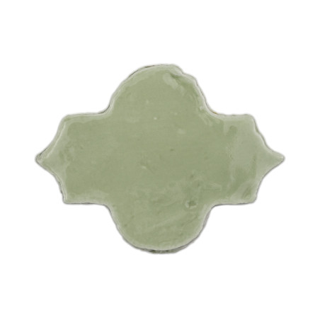 Un seul carreau en terre cuite verte brillante présente une forme décorative en forme de quadrilobe sur un fond blanc uni.