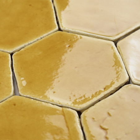 Carreaux hexagonaux en terre cuite avec une finition brillante, créant un motif chaleureux et terreux dans une disposition de su