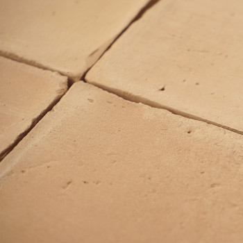 Terracotta tiles form a grid, displaying natural earthy tones and texture, creating a rustic flooring pattern.