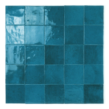 Een vierkante keramische tegel glinstert met een glanzend groenblauw glazuur en reflecteert subtiele lichtvariaties, afgezet teg