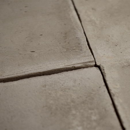 Quatre carreaux carrés en terre cuite se rejoignent, se croisant au centre, formant une surface de sol texturée.