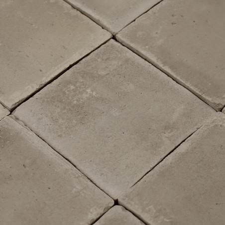 Carreaux carrés et lisses en terre cuite disposés selon un motif en grille, formant une surface aux tons neutres dans un décor i