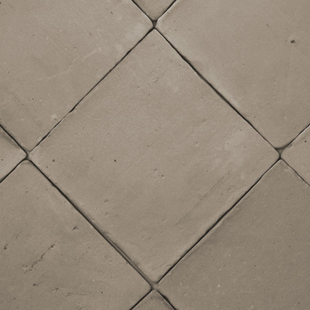 Terracotta tiles arranged diagonally, creating a diamond pattern on a flat, neutral-colored floor surface.