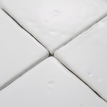 Witte terracottategels zijn dicht op elkaar gelegd en vormen een glad, verbonden oppervlak met subtiele kuiltjes, wat een verfij
