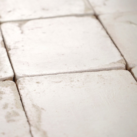 Square terracotta tiles are arranged in a grid, some displaying subtle wear, creating a rustic flooring appearance.