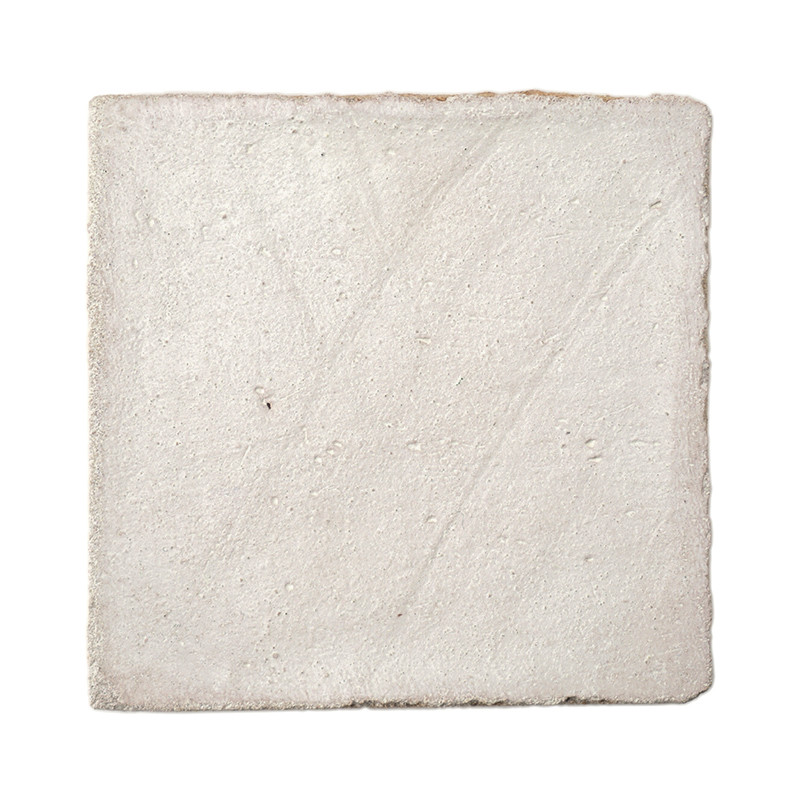 Square terracotta tile appears textured, resting against a plain white background, showcasing its rough, uneven surface.