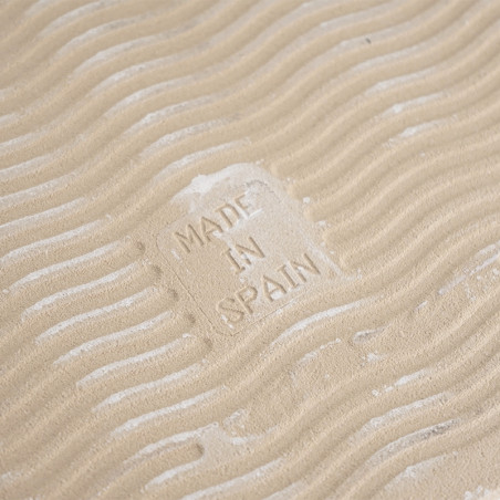 Um ladrilho cor de areia apresenta ondas em relevo, criando uma aparência texturizada. No centro está impresso o texto `MADE IN 