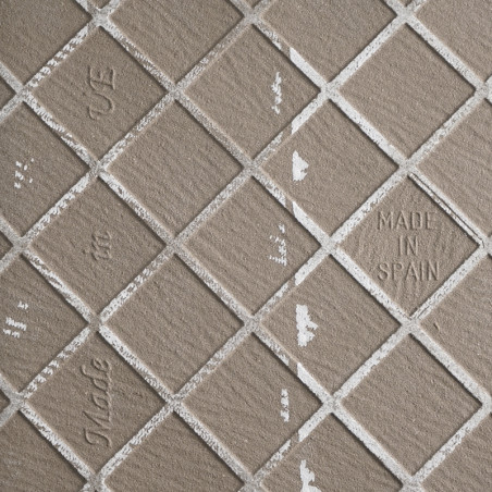 Image du carrelage : Carreaux carrés disposés en diagonale avec une surface texturée et mate. Le texte indique « MADE IN SPAIN »