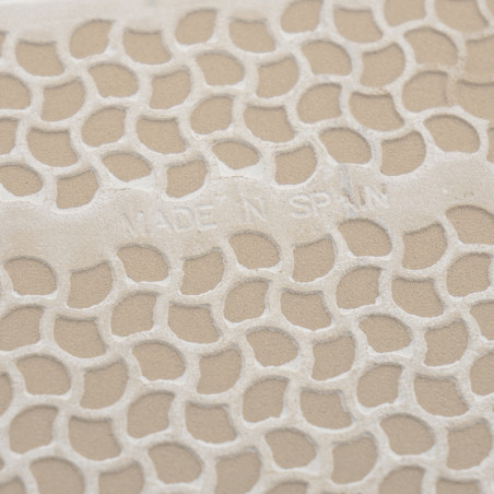 Azulejo texturizado con diseño de panal en relieve, que muestra el texto `MADE IN SPAIN`. La superficie tiene un fondo beige.