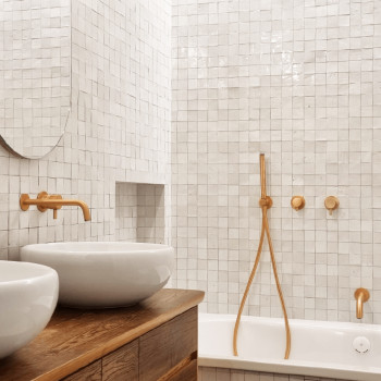 White terracotta tiles cover bathroom walls, arranged in a grid pattern, complementing wooden and ceramic bathroom fixtures.